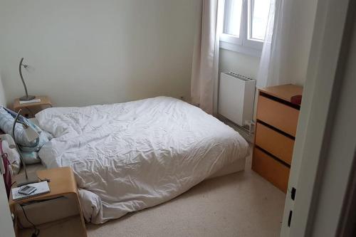 Cette petite chambre comprend un lit blanc et une commode. dans l'établissement Appartement spacieux aux portes de Paris, à Bagnolet