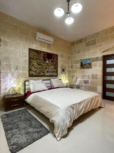 1 dormitorio con 1 cama grande y pared de piedra en Daner Ta’ Pantu House, en Kerċem
