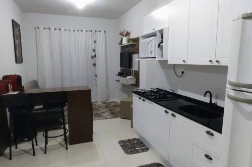 a kitchen with white cabinets and a table and a stove at Apto na Praia de Fora - Palhoça in Palhoça