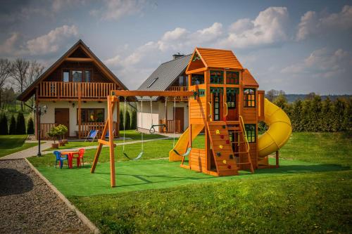 ein kleines Haus mit einem Spielplatz mit Rutsche in der Unterkunft Domki w Bieszczadach Nova Dolina in Średnia Wieś