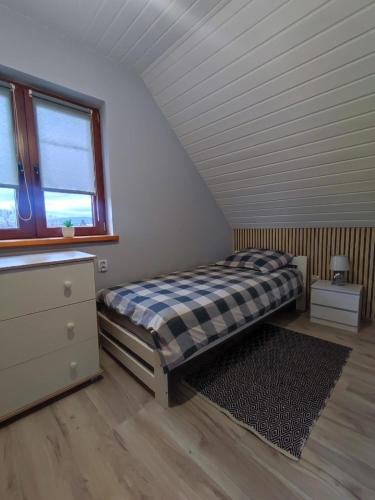 a bedroom with a bed and a dresser and a window at Domki w Bieszczadach Nova Dolina in Średnia Wieś