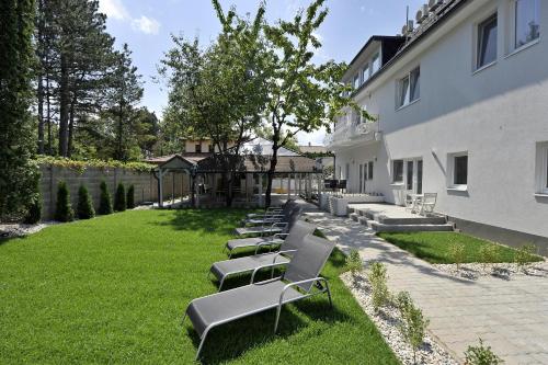 a row of benches sitting in the grass next to a building at Villa Oliver 1 Siófok in Siófok