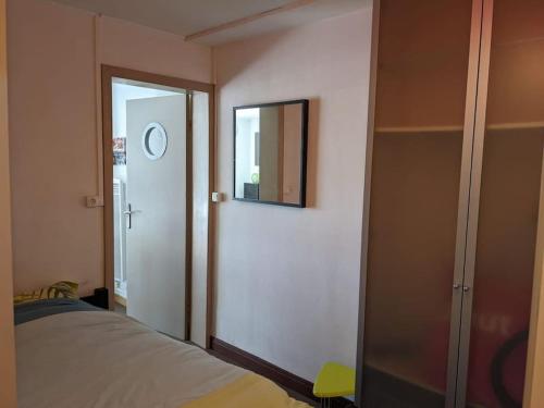 um quarto com uma cama e uma porta com um espelho em Appartement 4 voyageurs - Proche plage em Bray-Dunes