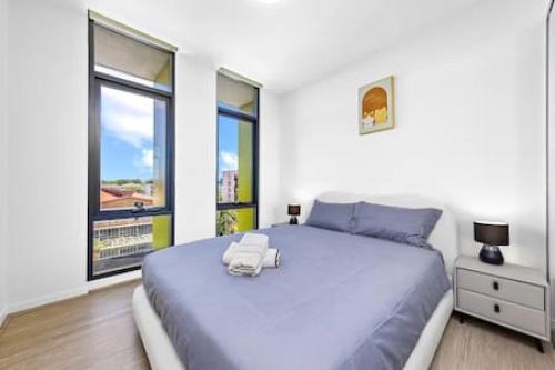 een slaapkamer met een groot blauw bed en 2 ramen bij comfy 2B apartment in Zetland in Sydney