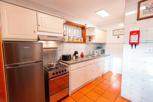 a kitchen with white cabinets and a stainless steel refrigerator at Quinta da Xistosa in Foz do Sousa