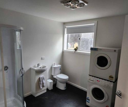uma casa de banho com um WC e uma máquina de lavar roupa em Whispering Woods Amore em Maryborough