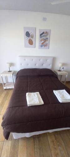 1 cama grande de color marrón en un dormitorio con 2 mesas en Quinta estilo campo La Calandria en Saladillo