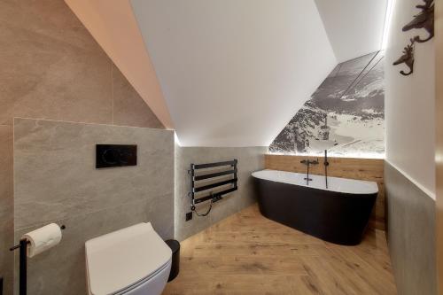 a bathroom with a black tub and a toilet at Tatra Wood House Boutique in Zakopane