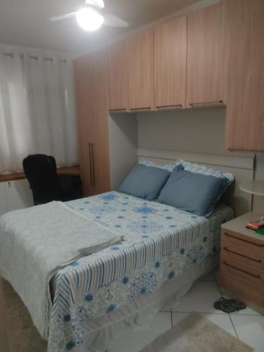 a bedroom with a bed with blue pillows at Ap 1 dormitório Praia Grande(canto do forte) 100m da praia in Praia Grande