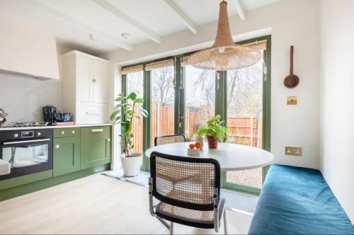 a kitchen with green cabinets and a white table with chairs at Spring Stays Cosy 2-Bed Residence with Free Parking in London