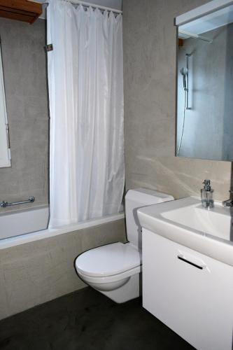 a white bathroom with a toilet and a sink at Haus Amasaas in Saas-Fee
