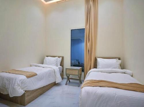 een slaapkamer met 2 bedden en een stoel bij شاليهات لاڤيرا in Hafr Al Baten