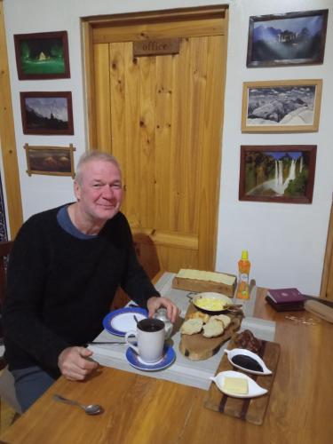 a man sitting at a table with a cup of coffee at La Frontera Bed & Breakfast, Valle Cochamó in Cochamó