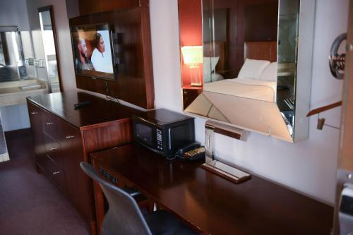 een kamer met een bureau, een televisie en een bed bij Relax Inn in Collinsville