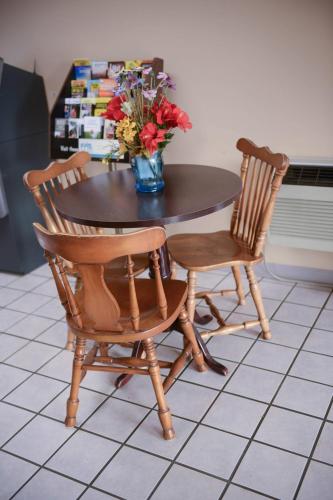 a table with two chairs and a vase with flowers on it at Relax Inn in Collinsville