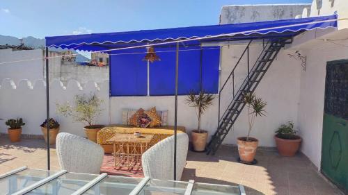 a patio with a table and chairs under a blue awning at Riad en el corazón de la Medina in Tétouan