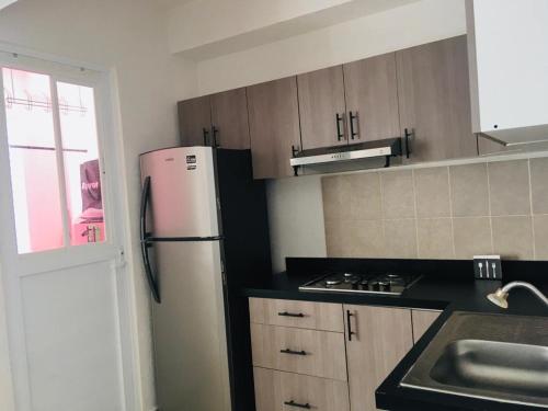 a kitchen with a white refrigerator and a sink at Ideal para estar en Familia in Cancún