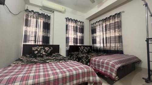a bedroom with two beds and two windows at Appayan Guest House (Baridhara) in Dhaka
