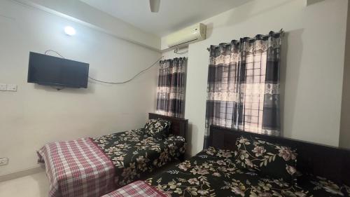 Schlafzimmer mit einem Bett und einem Flachbild-TV in der Unterkunft Appayan Guest House (Baridhara) in Dhaka