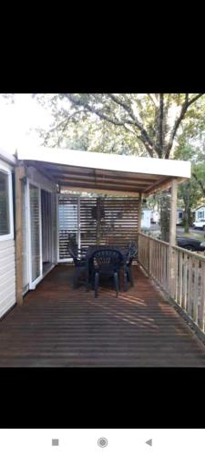 a porch with a table and benches on a deck at Le Kraken in Aureilhan