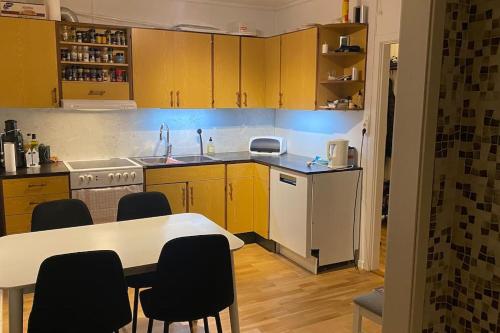 cocina con armarios amarillos, mesa y sillas en Skogstad Ferie og fritid, en Tromsø