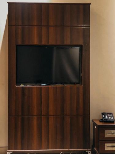 a flat screen tv on a wooden entertainment center at فندق فيلي للشقق الفندقية Filly Hotel Apartments in Hail