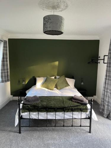 1 dormitorio con 1 cama con pared verde en Upsall Warren Cottage, en Middlesbrough