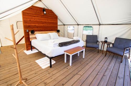 a bedroom in a tent with a bed and two chairs at Off Map Glamping in South Haven