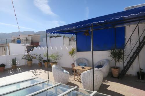 a patio with chairs and a table and a blue umbrella at Riad en el corazón de la Medina in Tétouan