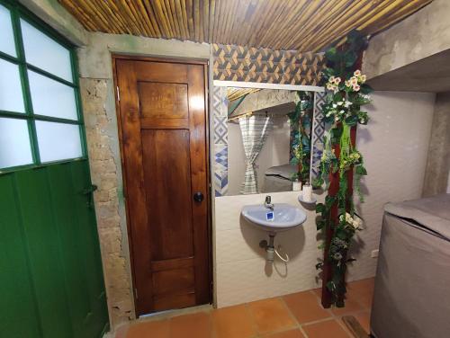 a bathroom with a sink and a wooden door at El Caña Bravo Posada, Alojamiento de Descanso in Duitama