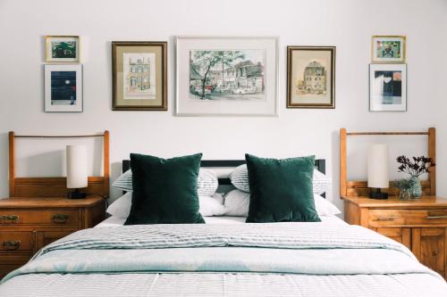 a bedroom with a bed with green pillows and pictures on the wall at The Old Homestead - Gorgeous backyard right in The Heart of Picton in Picton