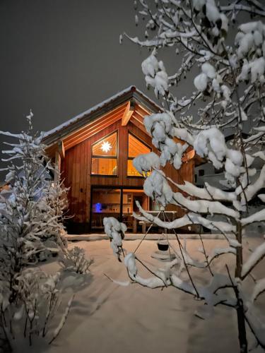 a log cabin in the snow with a tree at Ferienhaus Königsdorf - Urlaub im Tölzer Land in Königsdorf
