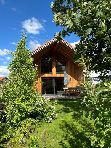 a wooden house with a tree in the yard at Ferienhaus Königsdorf - Urlaub im Tölzer Land in Königsdorf