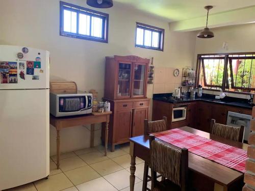 uma cozinha com um frigorífico branco e uma mesa com cadeiras em Residência familiar com piscina e área de lazer em São Gabriel