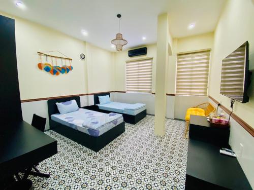 a room with two beds and a couch and a desk at SAM HOMESTAY HUE in Hue