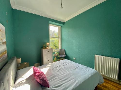 ein Schlafzimmer mit grünen Wänden und einem Bett mit rosa Kissen in der Unterkunft Traveller Award Winner 2023 - Edinburgh Apartment with 3 Beds in Edinburgh