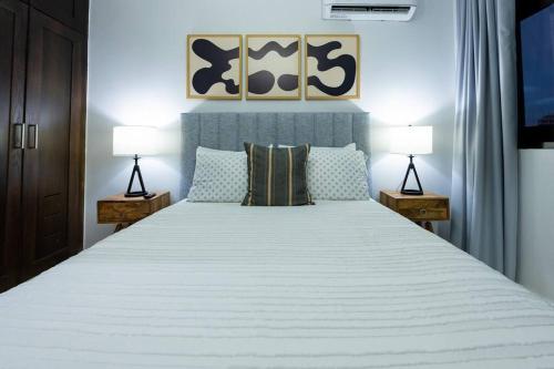 a bedroom with a large white bed with two lamps at Modern 2BR in La Trinitaria Sti No in Santiago de los Caballeros