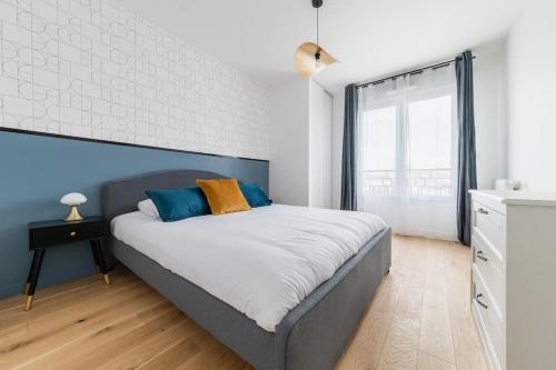 une chambre avec un grand lit avec un mur bleu dans l'établissement L'Elégante Oasis - grand T2 aux portes de Paris, à Saint-Ouen