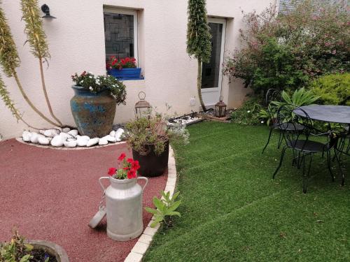 a garden with a table and a vase with flowers at Ty Pempoul - logement 2 chambres - 100 m de la plage in Saint-Pol-de-Léon