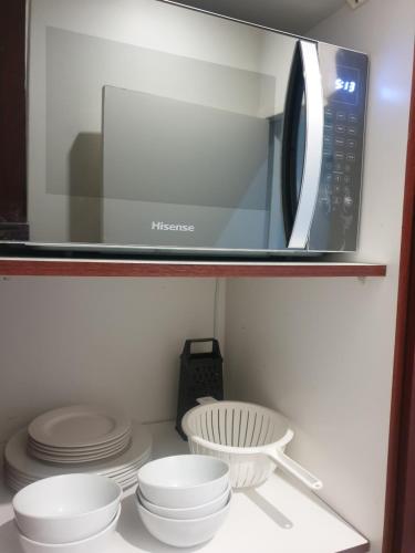 a microwave sitting on a shelf with plates and bowls at Casa La Moore Self Catering Accomodation in Durban