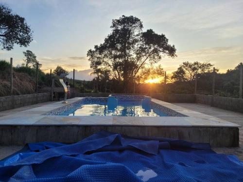einen Pool mit Sonnenuntergang im Hintergrund in der Unterkunft Fazenda centenária no Sul de MG 