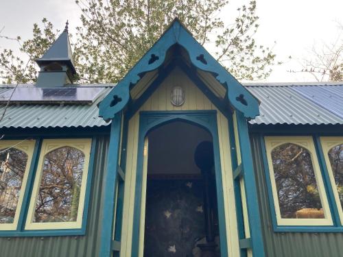 a small house with a blue roof and a door at Enchanting Hand Painted Tabernacle with Hot Tub in Bude