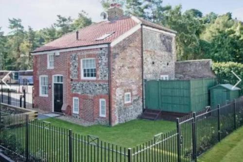 una casa de ladrillo con una valla delante de ella en Detached Pet Friendly Cottage, 2 parking spaces en Norwich