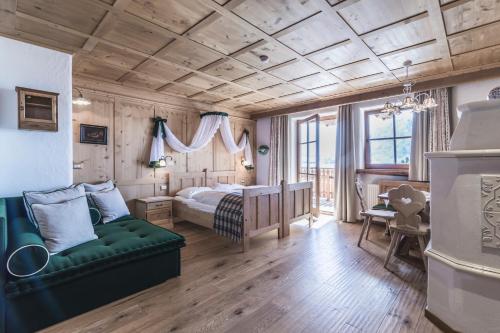 ein Schlafzimmer mit einem Bett und einem grünen Sofa in der Unterkunft Almhotel Col Raiser in St. Christina in Gröden