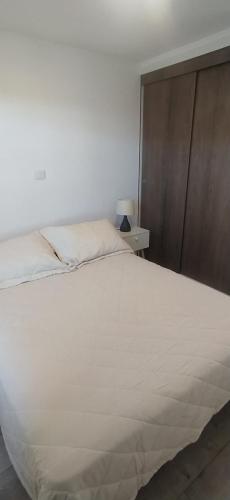 1 dormitorio con 1 cama blanca grande y cabecero de madera en Moderno departamento con balcón en IslaTeja, Valdivia en Valdivia