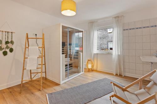 a living room with a chair and a glass door at GIPFELSTÜRMER Winterberg-Niedersfeld mit Infrarotsauna, Yoga, Netflix, WLAN in Winterberg