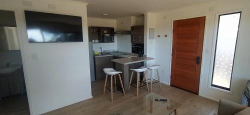 cocina con encimera y taburetes en una habitación en Moderno departamento con balcón en IslaTeja, Valdivia en Valdivia