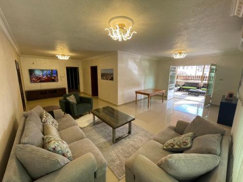 ein Wohnzimmer mit zwei Sofas und einem Tisch in der Unterkunft Gather 'n' Gab Gateway family apartment in Amman