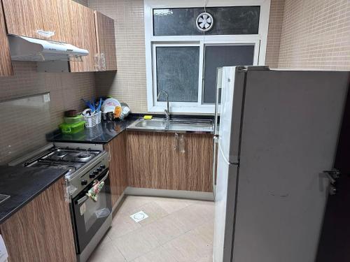 a kitchen with a refrigerator and a sink and a window at Ladies Hostel in Ajman سكن بنات بعجمان in Ajman 