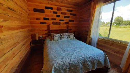 um quarto com uma cama num chalé de madeira em ENTRE PINOS Y LUCEROS ACOGEDORA CABAÑA RÚSTICA em Villarrica